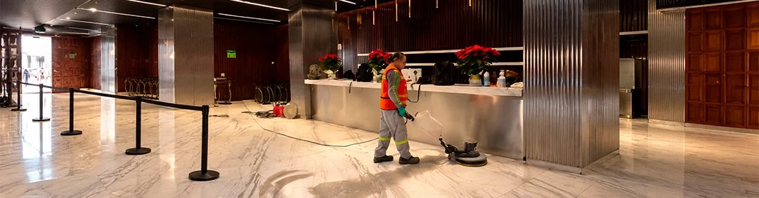 Operaria de limpieza usando una pulidora en el área común de un corporativo durante un servicio de mantenimiento de pisos.