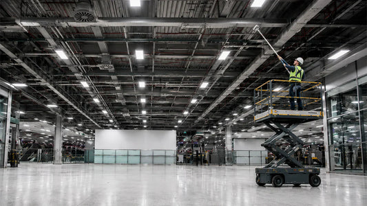 Técnico en plataforma de elevación realizando limpieza en altura de techos, vigas y ductos dentro de una nave industrial en el Bajío.